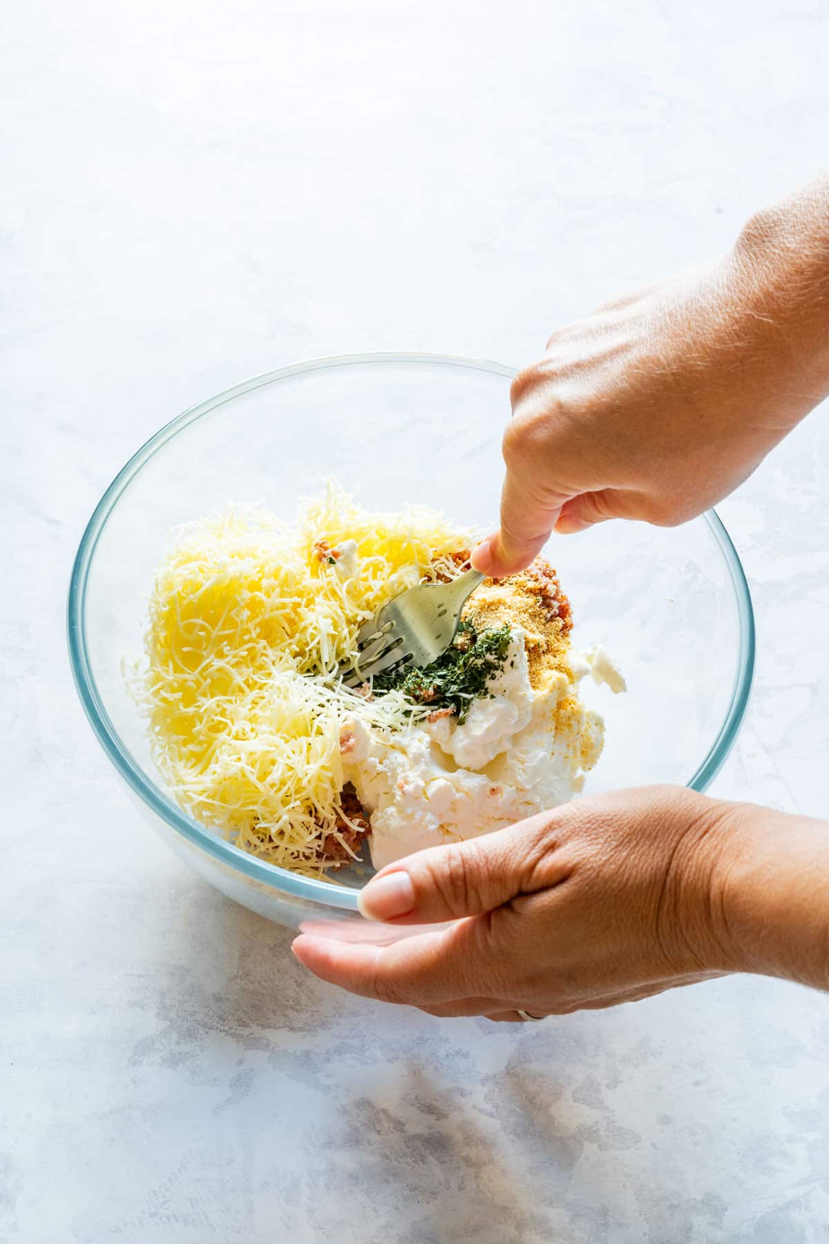 Mixing cream cheese, cheddar and seasonings for a bacon olive cheese ball.