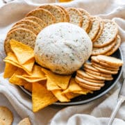 Cheese ball platter with crackers, tortilla chips and a small glass of hot honey.