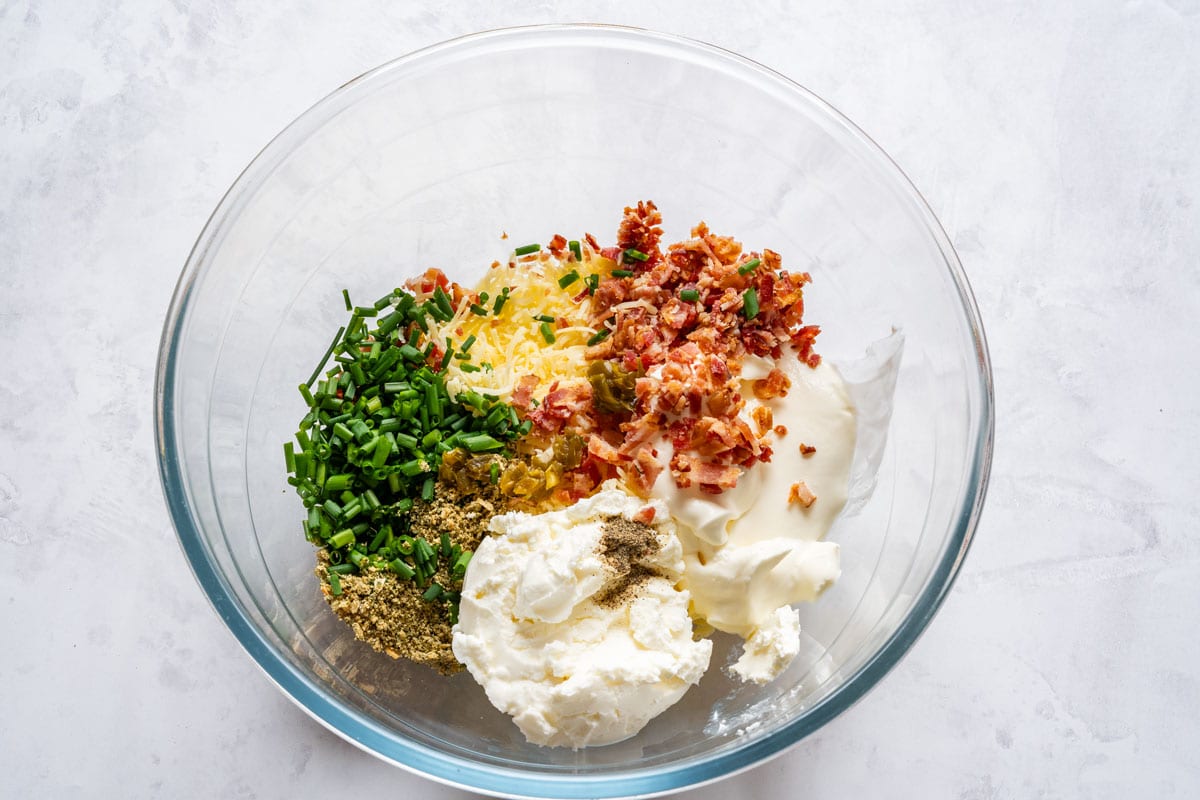 Cream cheese, sour cream, cheddar, bacon, chives, ranch seasoning and jalapeños in a bowl.