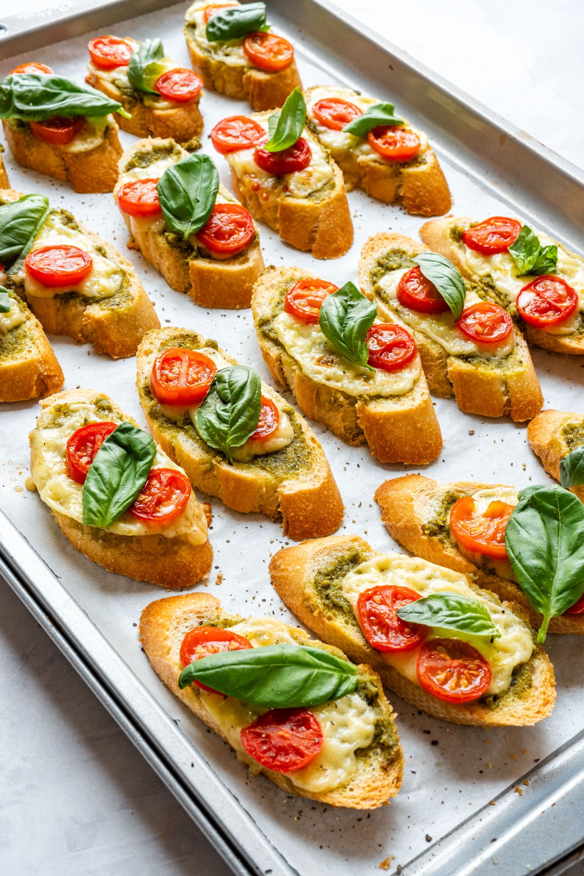 Freshly baked crostini with melted cheese, cherry tomatoes and basil leaves.