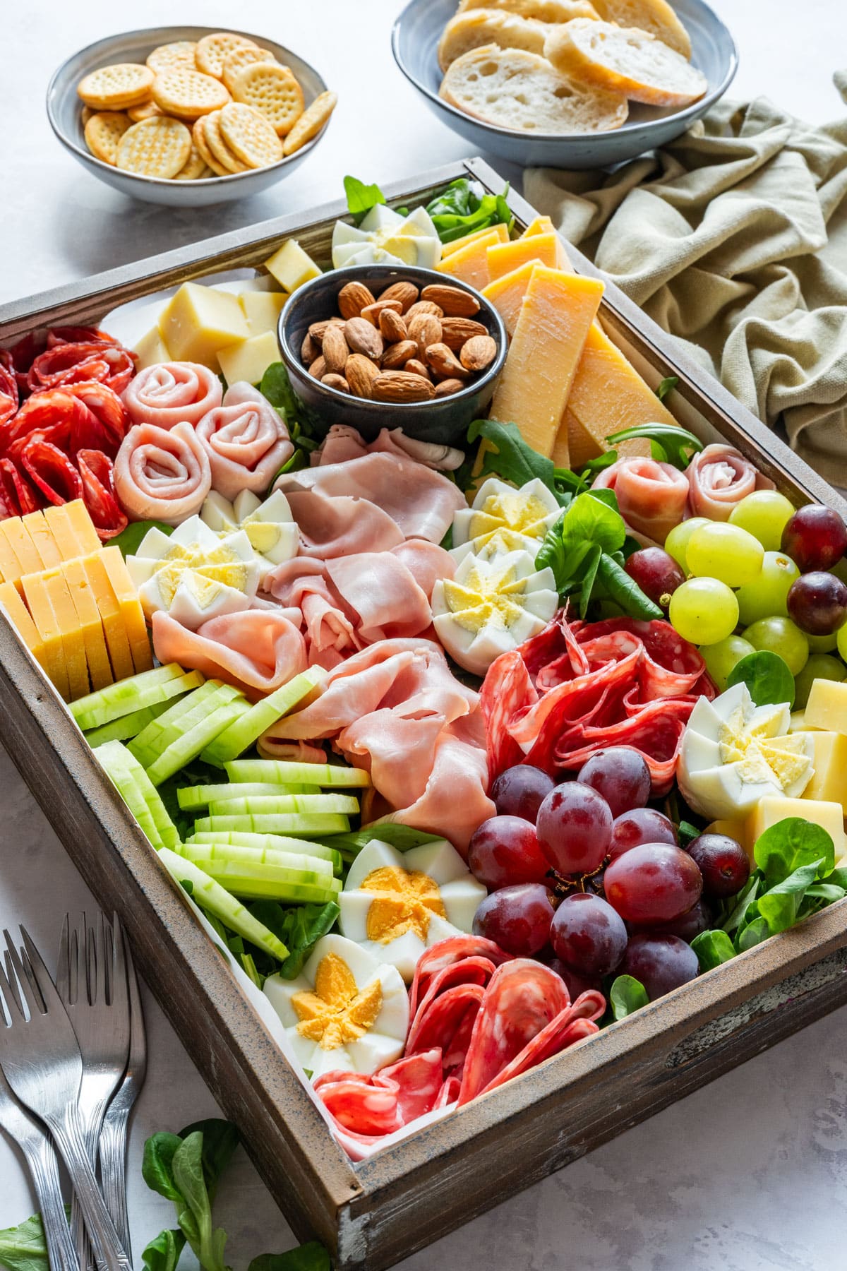 Spring charcuterie board with salami, ham, cheese, cucumber, grapes, almonds and hard-boiled eggs cut like flowers.