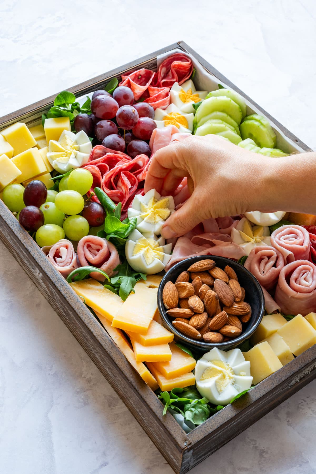 Hand placing a flower-shaped hard-boiled egg onto the board.