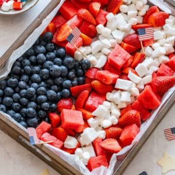 4th of July fruit platter arranged like an American flag, with a blueberry corner and rows of strawberries, watermelon, coconut and mini marshmallows.