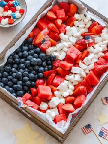 4th of July fruit platter arranged like an American flag, with a blueberry corner and rows of strawberries, watermelon, coconut and mini marshmallows.