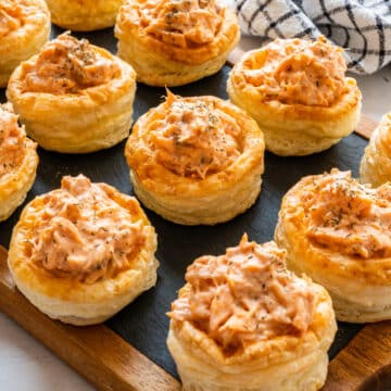 Salmon vol-au-vents with creamy salmon filling and dried dill on a slate serving board.