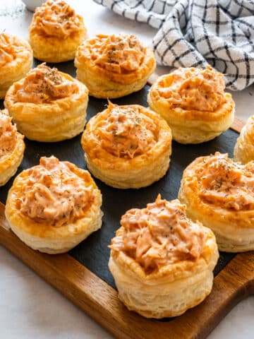 Salmon vol-au-vents with creamy salmon filling and dried dill on a slate serving board.
