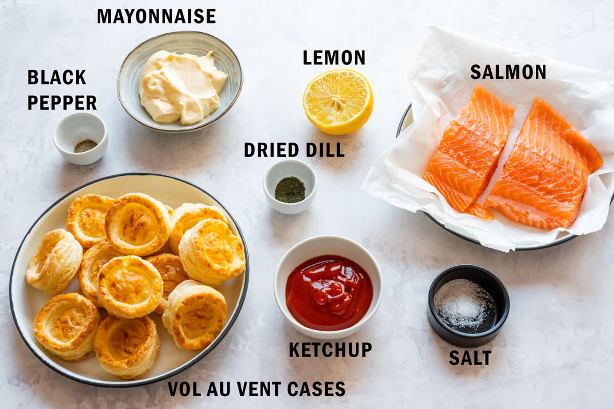 Ingredients for salmon vol-au-vents including salmon fillet, puff pastry cases, mayonnaise, ketchup, lemon, dried dill, salt and black pepper.