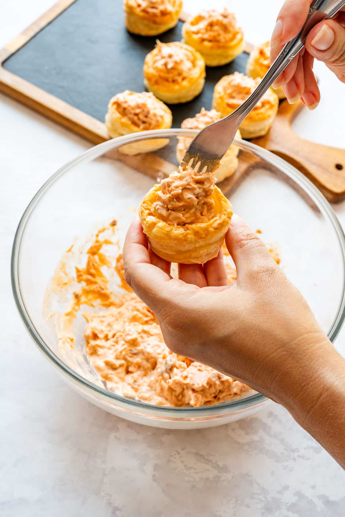 Filling a puff pastry case with the creamy salmon mixture using a fork.
