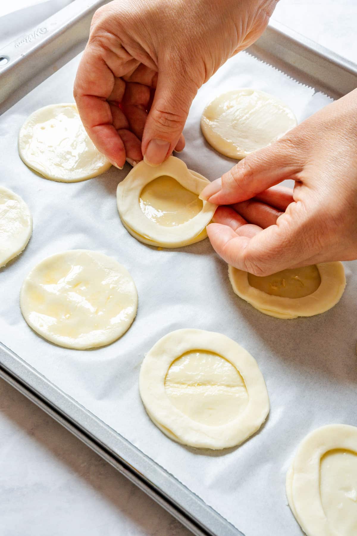 Placing a pastry ring on top of an egg-washed base to build a vol-au-vent case.