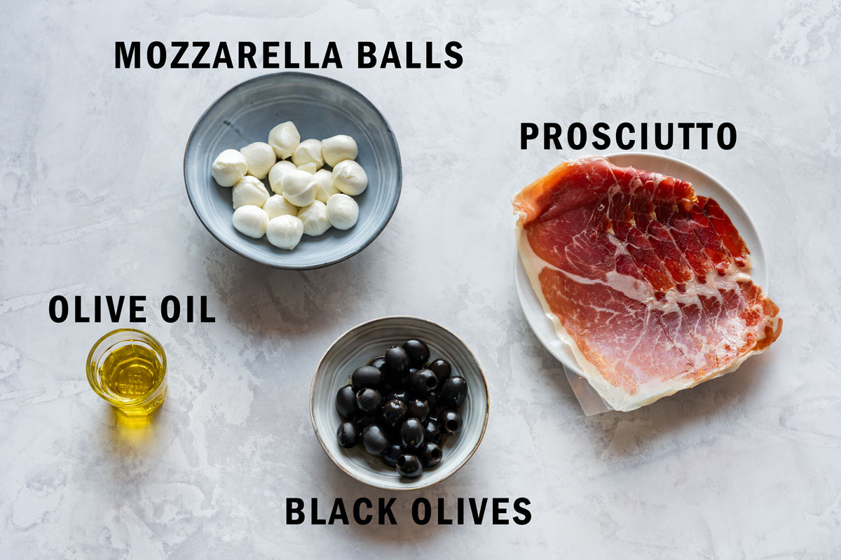 Ingredients for mozzarella eyeballs: mini mozzarella balls, sliced prosciutto, pitted black olives and olive oil.