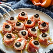 Four ingredients, about 10 minutes and no cooking. Mini mozzarella balls are wrapped in prosciutto with black olive pupils. They’re a savory Halloween appetizer you can assemble a day ahead.