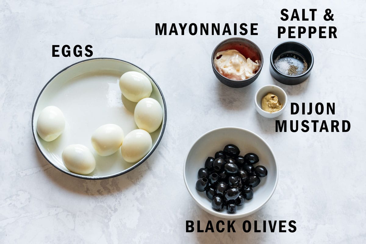 Peeled hard-boiled eggs, pitted black olives, mayonnaise, Dijon mustard and a small bowl of salt and pepper.