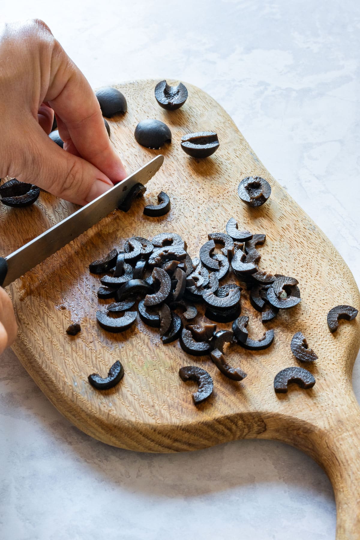 Slicing black olive halves into thin half-moon pieces for the spider legs.