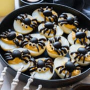 Spider deviled eggs for Halloween have a classic mayo and Dijon filling topped with little spiders cut from black olives. Thin half-moon slices make the legs, with half an olive for each body. You can make them the night before, but add the optional candy eyes just before serving so the color doesn’t bleed.